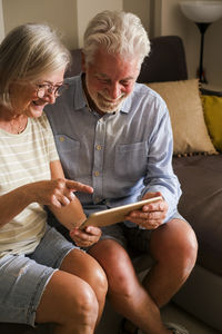 Senior using phone while sitting on sofa at home