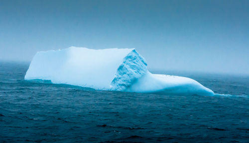 Scenic view of iceberg against clear blue sky