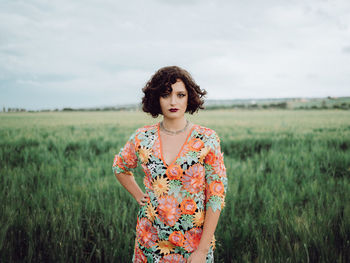 Young woman standing on field against sky