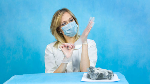 Portrait of a beautiful young woman standing against blue wall