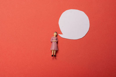 Full length of woman standing against red wall