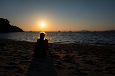 Man on beach against sky during sunset