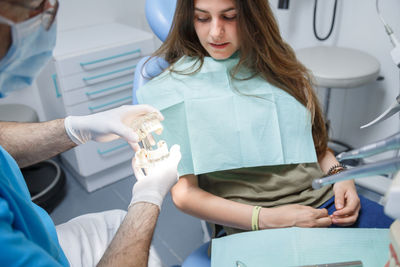 Midsection of dentist holding dental equipment by patient in clinic