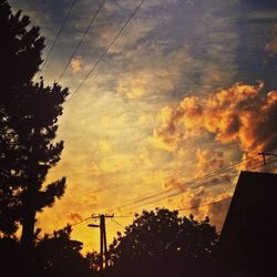 Low angle view of power lines against cloudy sky