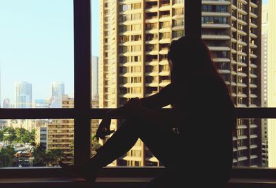 Side view of silhouette woman against buildings in city