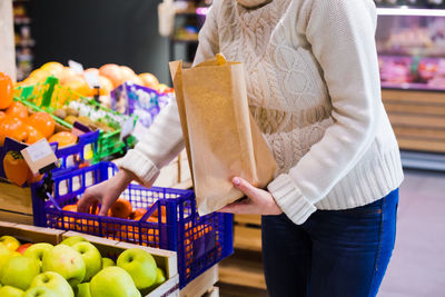 Midsection of woman holding ice cream at market