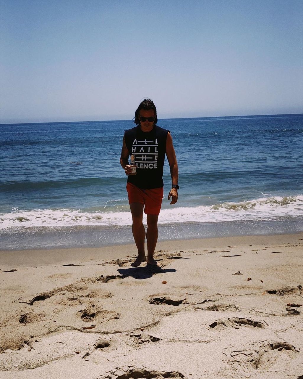 beach, sea, land, water, horizon over water, one person, sky, real people, scenics - nature, leisure activity, horizon, beauty in nature, standing, full length, casual clothing, lifestyles, front view, sand, nature, outdoors, teenager, shorts, adolescence