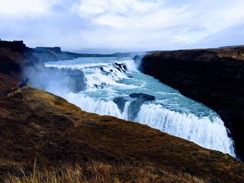 Scenic view of waterfall against sky