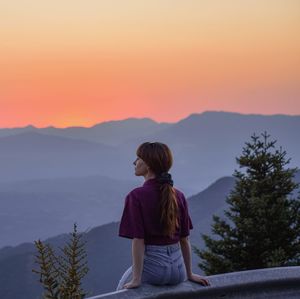 Rear view of woman standing against sky during sunset