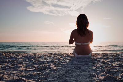Rear view of woman on beach during sunset
