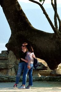 Full length portrait of woman standing against tree