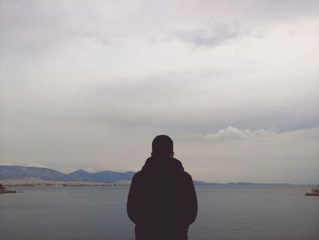 Rear view of man looking at sea against sky