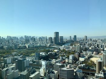 Aerial view of buildings in city against clear blue sky