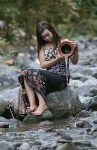 Portrait of woman sitting on rock