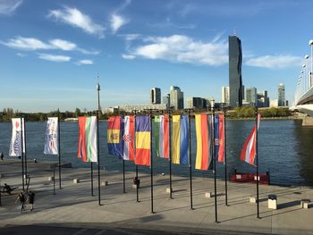 Multi colored flags on river against buildings in city