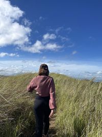 Rear view of woman jumping against sky