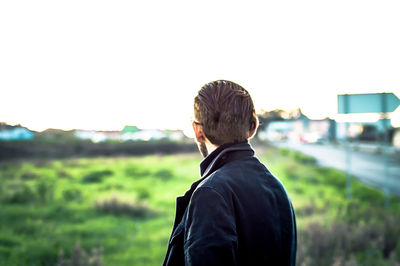 Rear view of man standing on field against sky