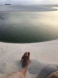 Low section of person on beach against sky