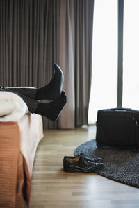 Low section of businessman relaxing on bed in hotel room