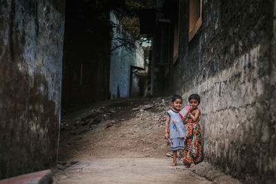 Full length portrait of boy standing with sister on footpath