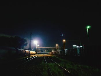 Railroad tracks against sky at night