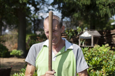 Gardener in dirty work clothes and boots holds garden tools, pitchforks,seasonal