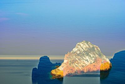 Scenic view of rocks on sea shore against sky