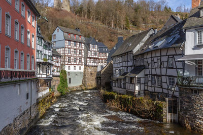 Houses by river against buildings