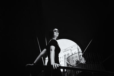 A pretty charming middle-aged woman in a black dress and sunglasses strolls through in the stairs