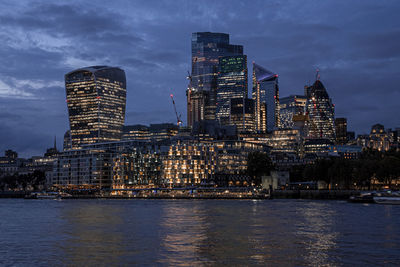 View of illuminated modern financial district skyscrapers from river thames