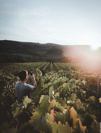 Man photographing on field against sky