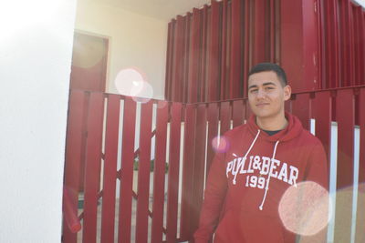 Portrait of young man standing by fence