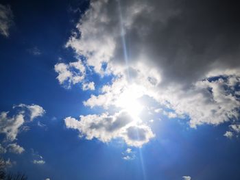 Low angle view of sunlight streaming through clouds