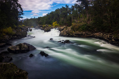 Scenic view of waterfall in forest against sky