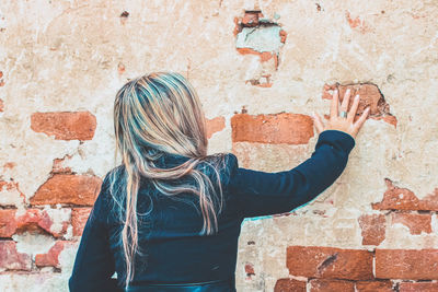 Rear view of woman standing against wall