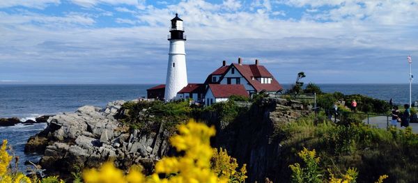 Lighthouse by sea against sky