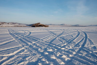 Car tracks go across the frozen great lake to the island against the backdrop of the village.