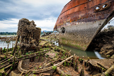 Abandoned boat on shore against sky