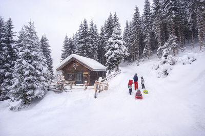 Austria, altenmarkt-zauchensee, family with sledges at wooden house at christmas time