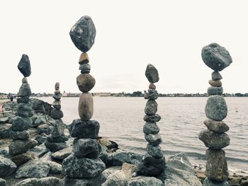 Stack of stones by lake against sky
