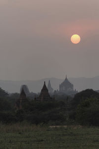 Temple amidst trees against sky at sunset