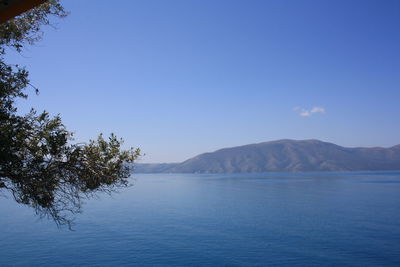 Scenic view of sea and mountains against blue sky