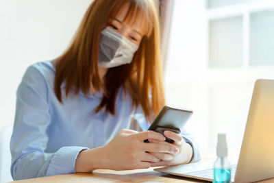 Woman using mobile phone while sitting on table