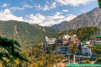 Scenic view of townscape by mountains against sky