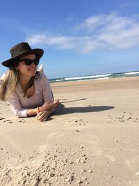 Smiling woman lying on sand against sea at beach