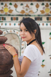 Asian woman in a white t-shirt looking at a camera at the wat arun temple in thailand.