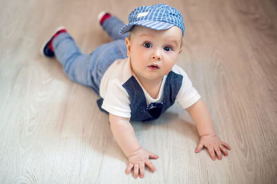 Gay boy kid blonde in a cap and pants lying on the floor