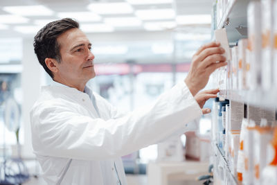 Pharmacist arranging medicines on shelf in store