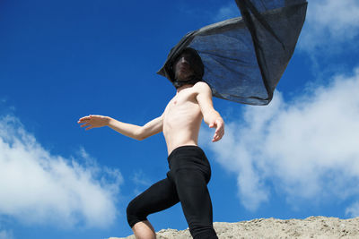 Low angle view of shirtless man with black fabric
