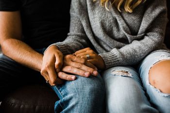 Midsection of friends sitting on sofa at home